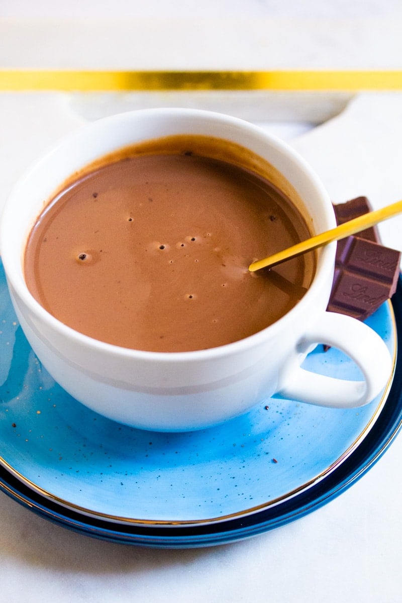 Italian Hot Chocolate in a white cup with Lindt chocolate pieces on the side.