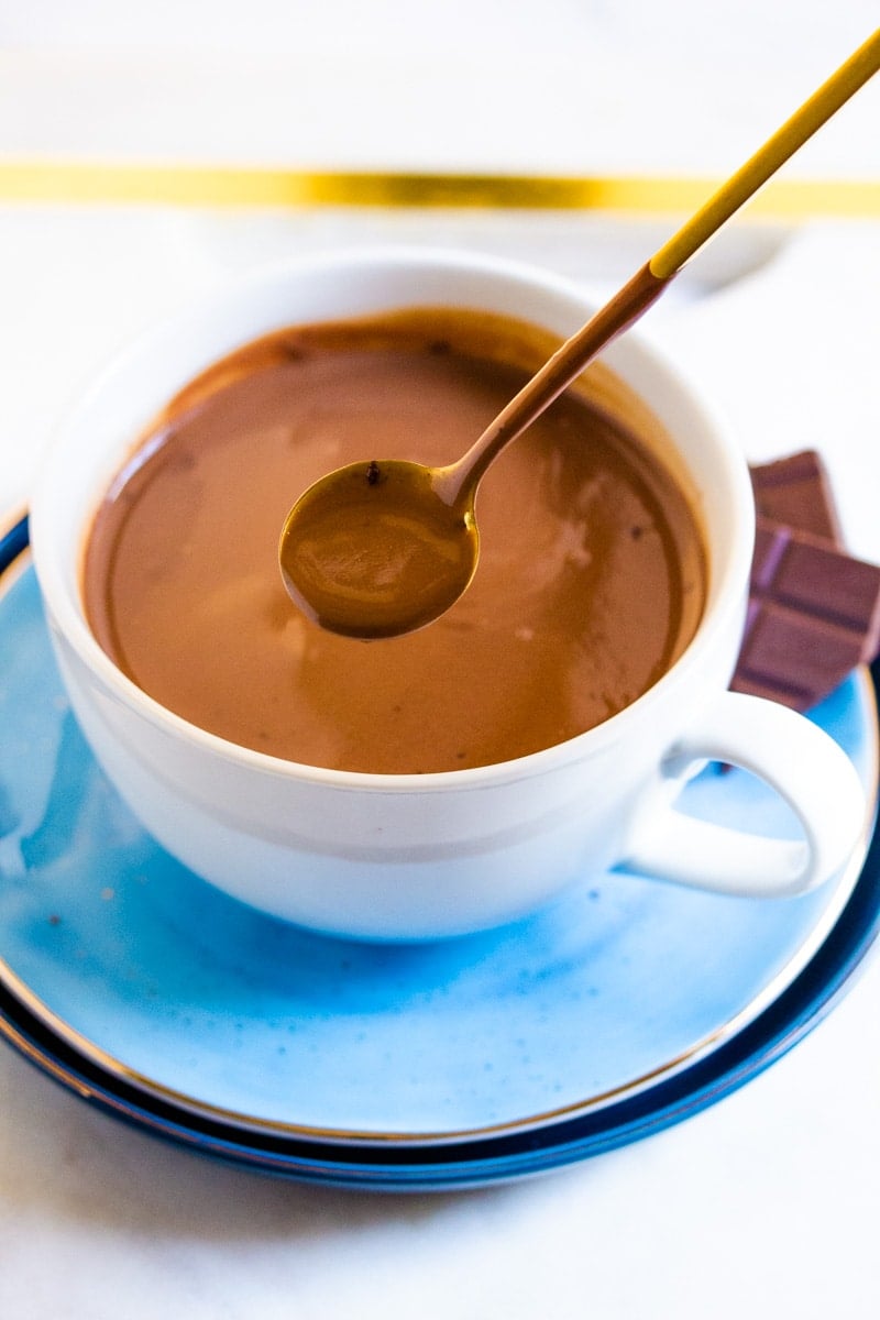 Hot chocolate in a cup with a chocolate-covered spoon.