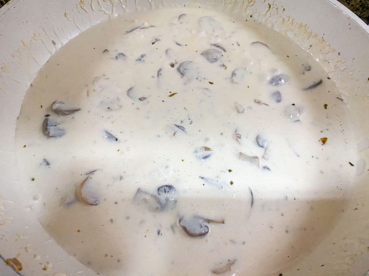 final shot of completed creamy mushroom sauce in a white saucepan for easy grilled chicken breasts