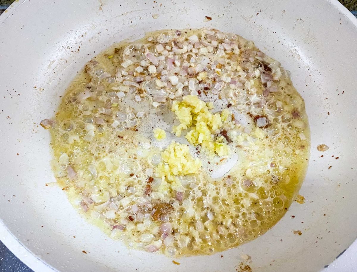 bubbling butter in a pan with red onions and minced garlic sautéing in the same pan as the chicken was cooked in for this one pan chicken recipe