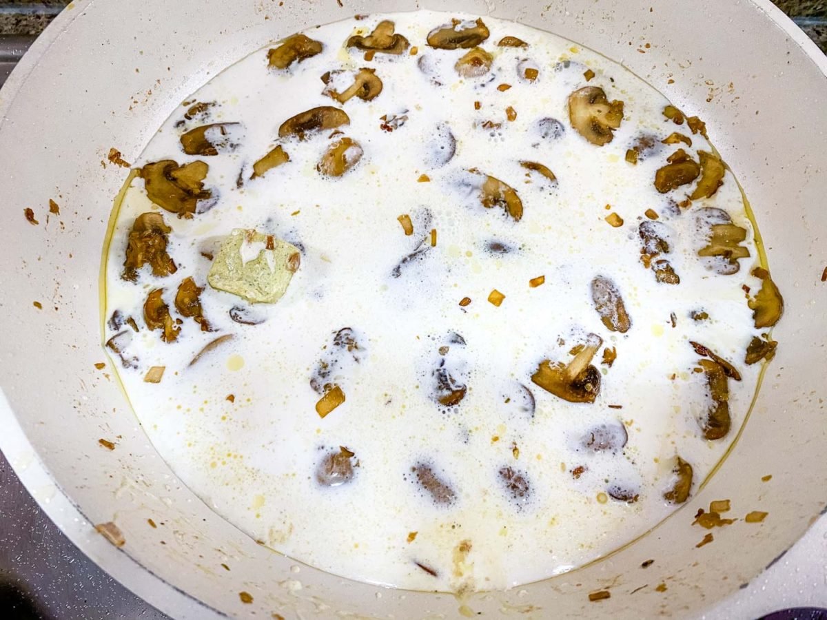 creamy keto mushroom sauce for chicken after adding cream and boullion cube to mushrooms and aromatics, prior to thickening with parmesan cheese