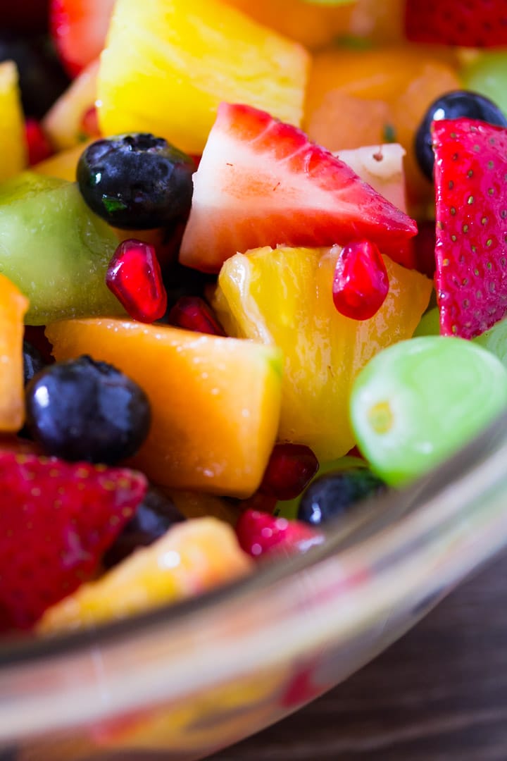 A close up shot of fruit salad coated in a honey and mint dressing.