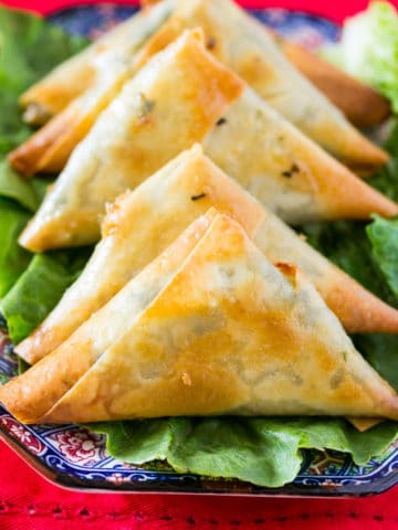 Baked Spinach & Feta Cheese Samosa on a bed of green lettuce on a beautiful blue plate