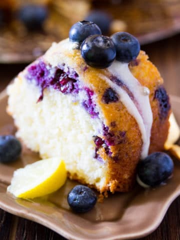 A slice of blueberry lemon cake drizzled with cream cheese icing