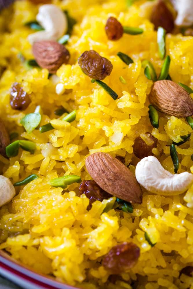 Close up shot of sweet zarda topped with raisins, pistachios, cashews, and almonds. 