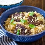 beef yakhni pulao in a blue bowl served with a side of raita