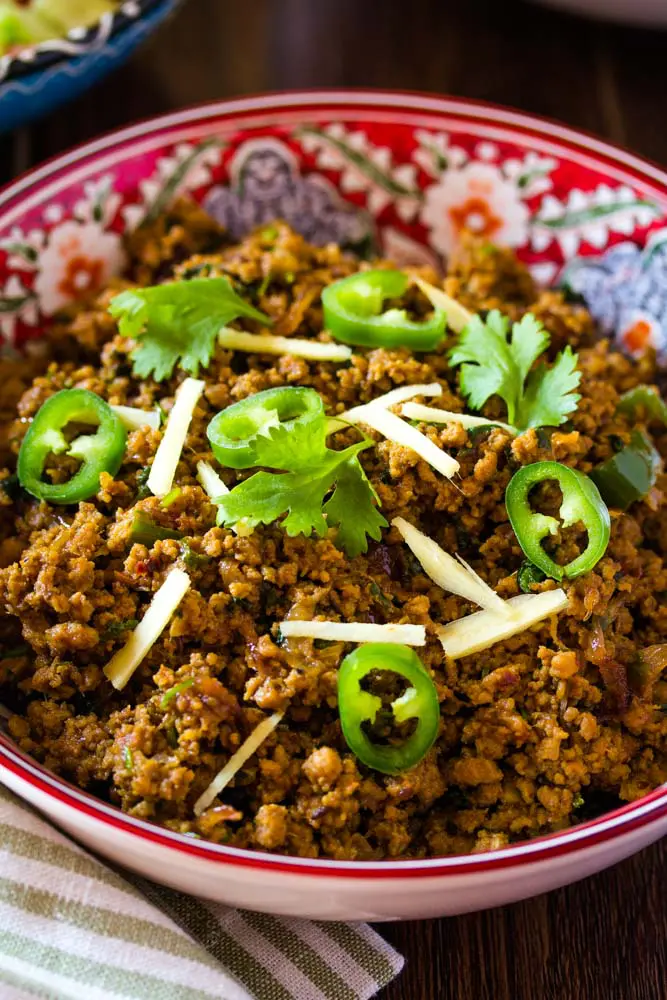 Pakistania keema servido en un tazón rojo con arroz y ensalada