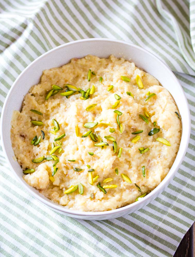 Egg Halwa served in a white bowl topped with slivered pistachios.