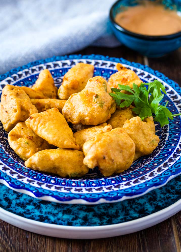 Chicken pakora on a blue plate served a dip 