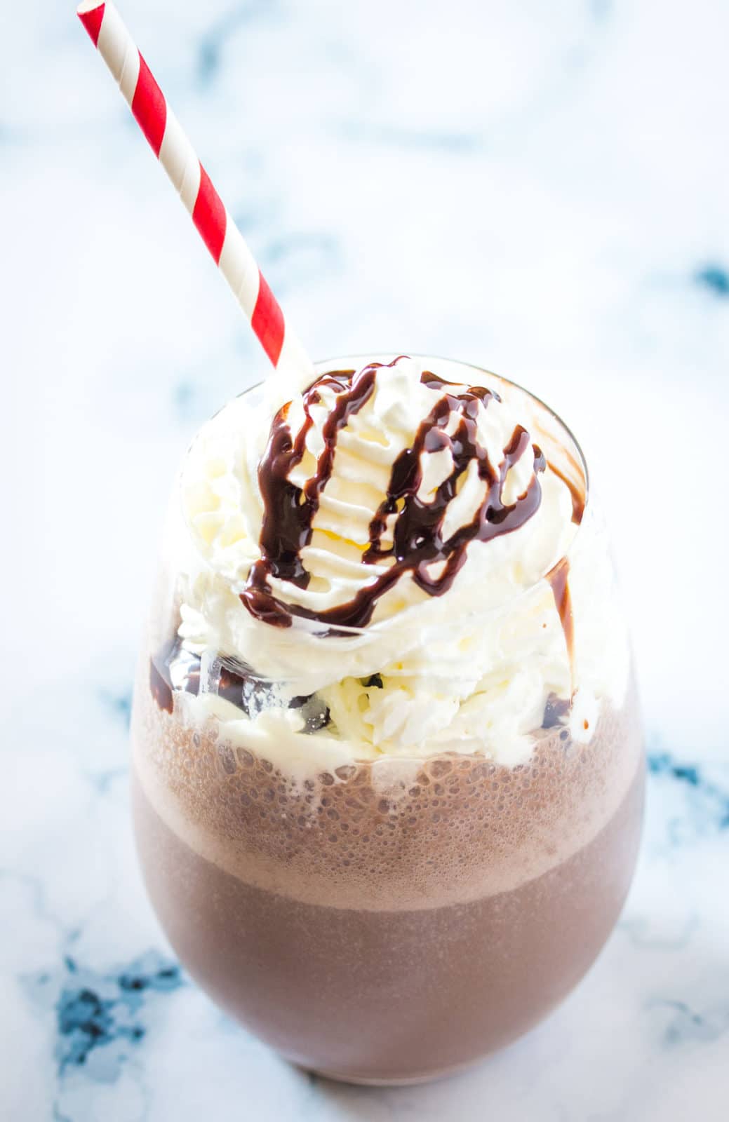 Chocolate banana milkshake in a round glass topped with whipped cream and syrup.