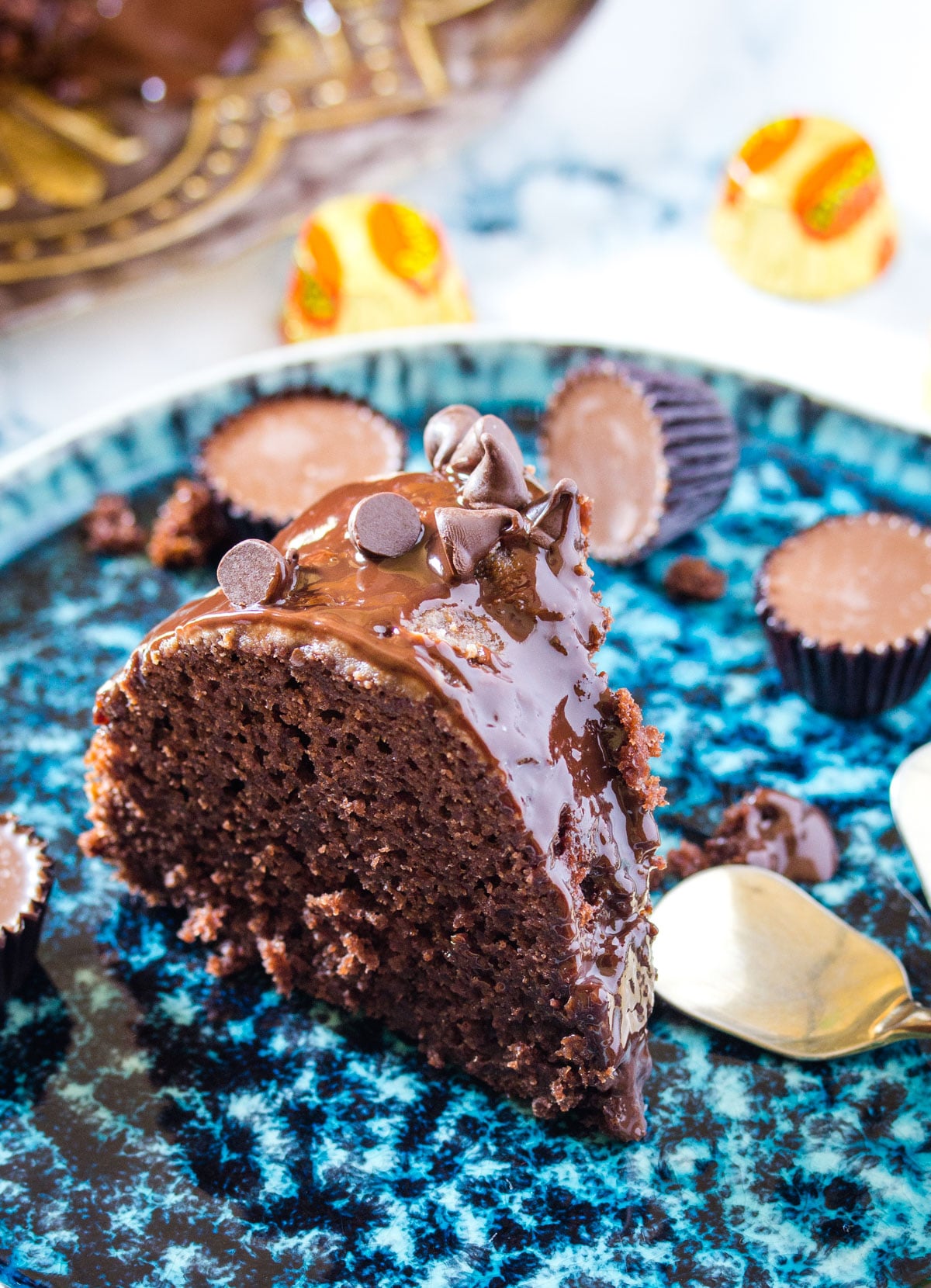 close up of triple chocolate bundt cake on a blue plate laid out on a marble background.