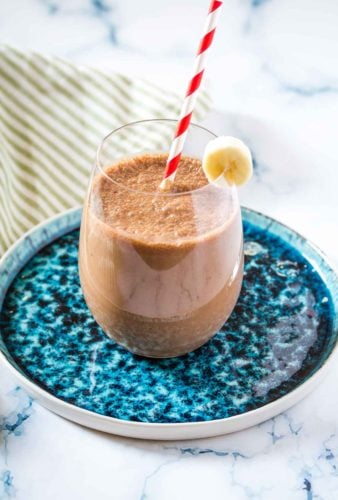 coffee banana smoothie in a round glass on a turqoise plate.