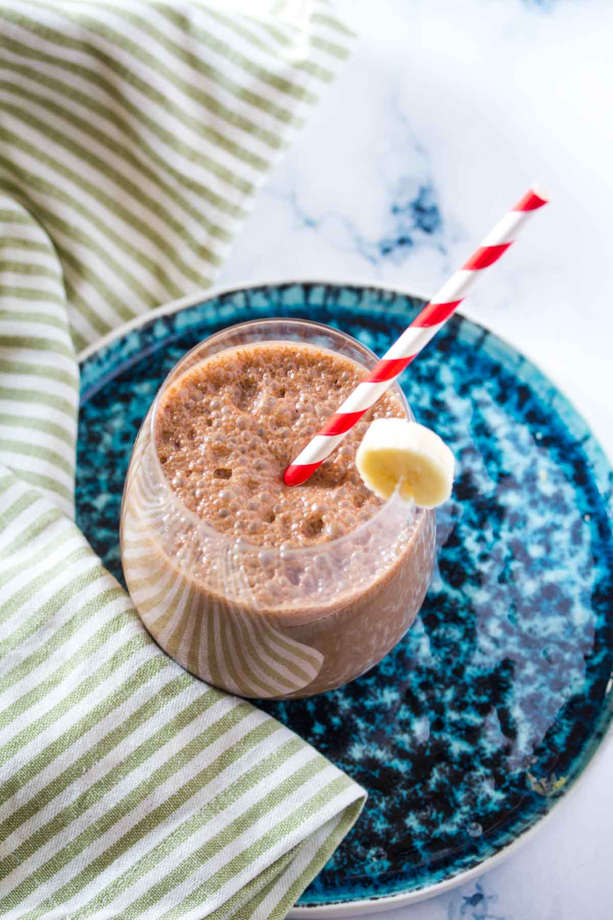Coffee Smoothie in a round glass with a red and white striped straw.