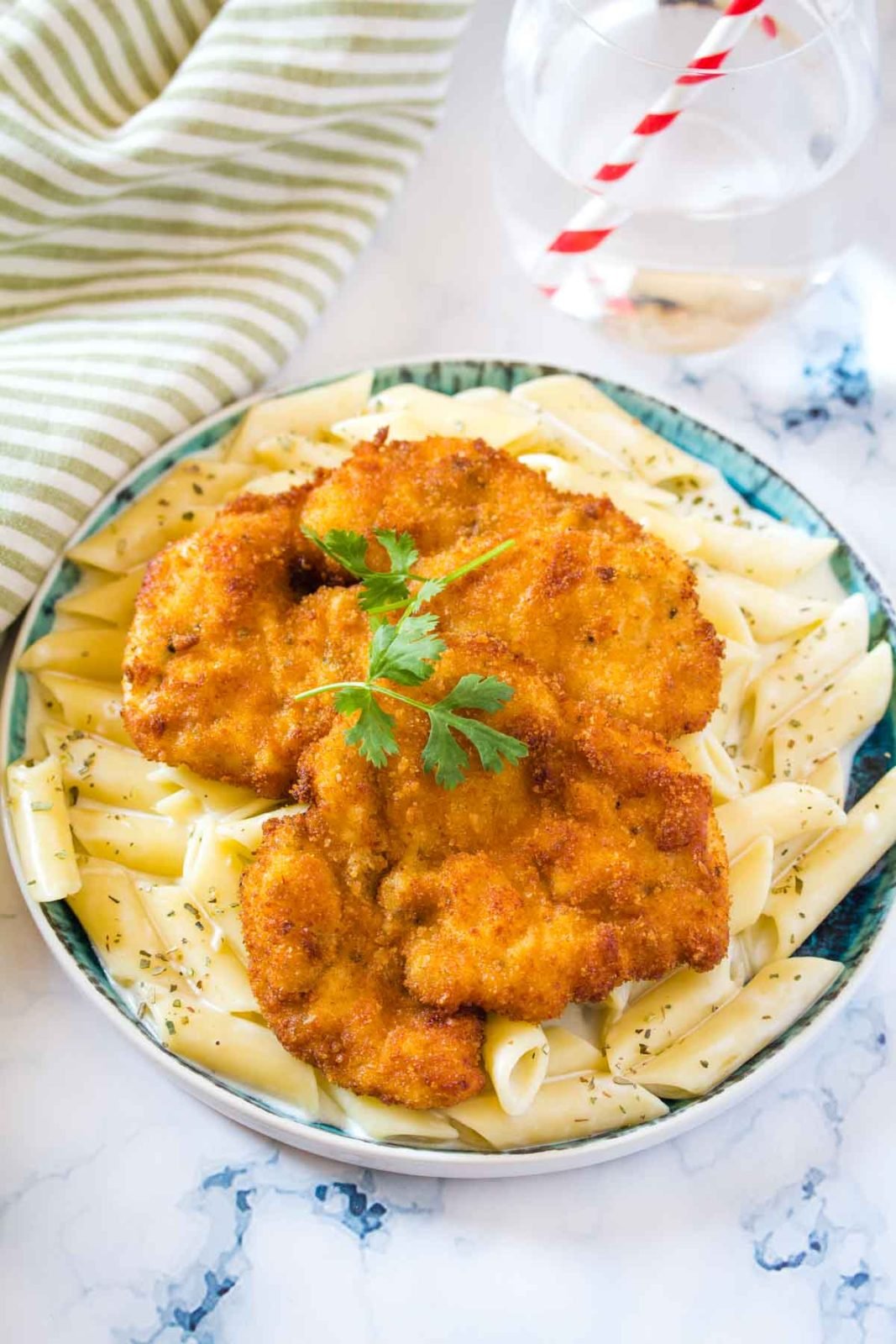 Two Breaded Chicken Cutlets served with Garlic Pasta on a blue plate