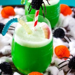 Green polyjuice potion in a glass with spooky decorations.