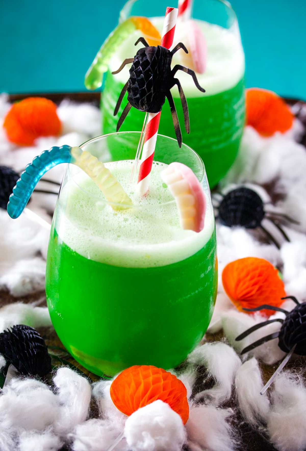 Polyjuice Potion in a round glass decorated with gummy worms and Halloween decorations.