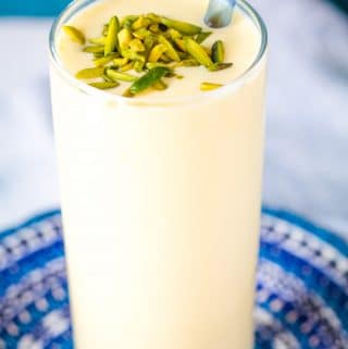 Mango Lassi in a tall glass with a blue straw.