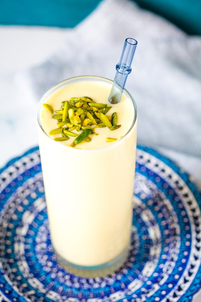 mango lassi in a tall glass on a blue plate
