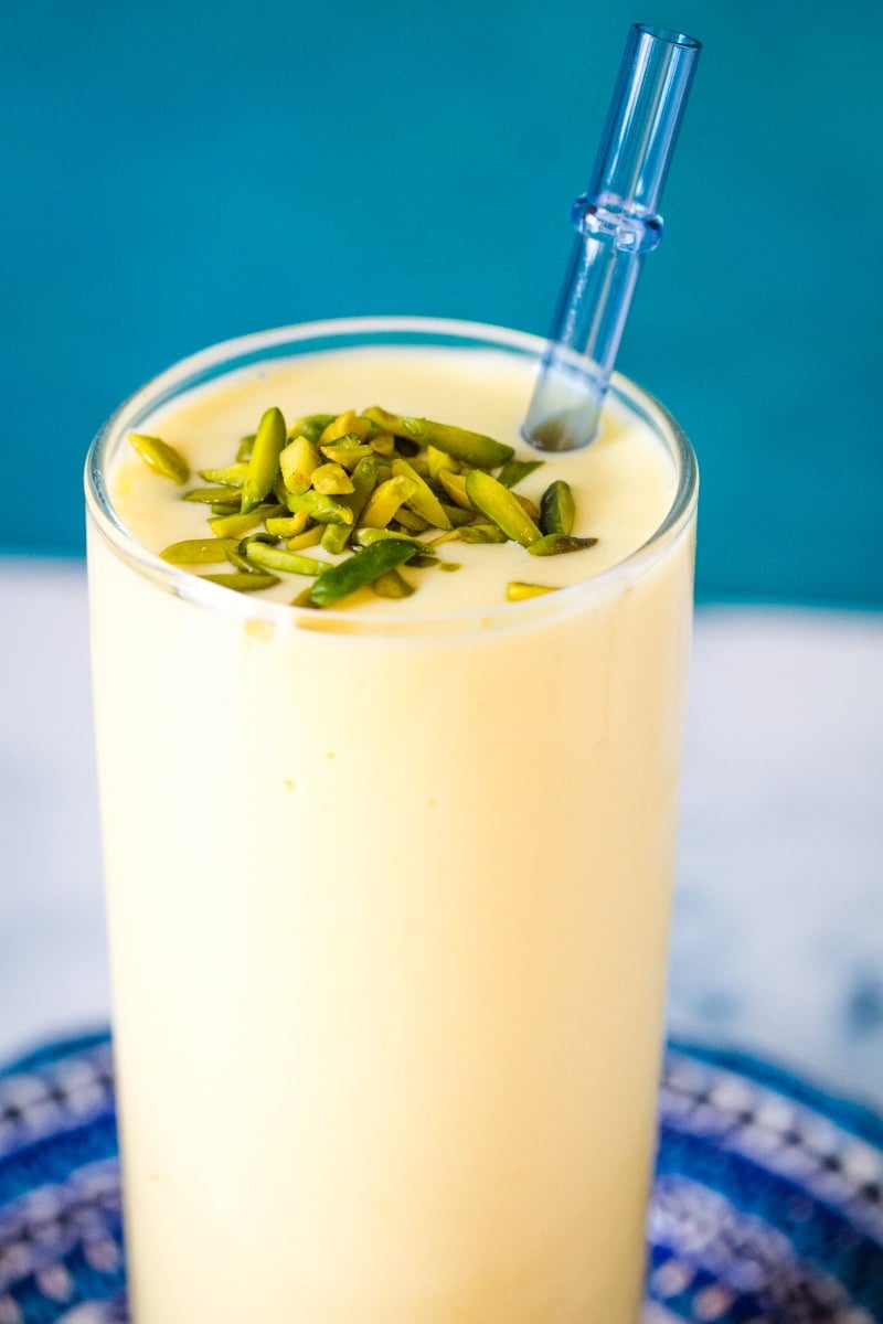 close up of mango lassi garnished with slivered pistachios