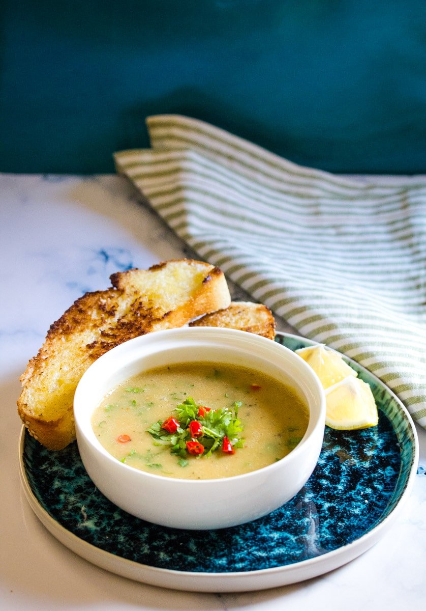 instant pot lentil soup in a white bowl served with buttered bread.