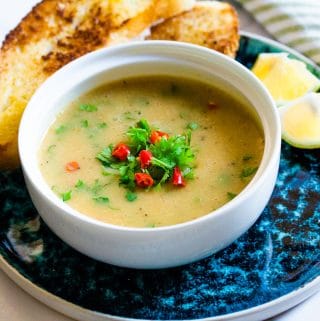 yellow lentil soup in white bowl placed on a blue plate.