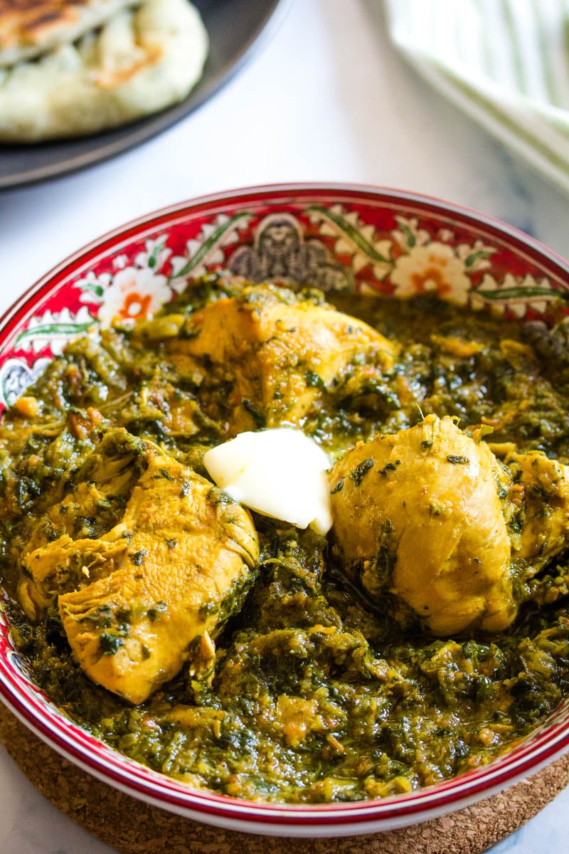 Saag chicken made with frozen spinach in a red patterned bowl. 