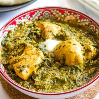 palak chicken topped with butter, and served in a red bowl.