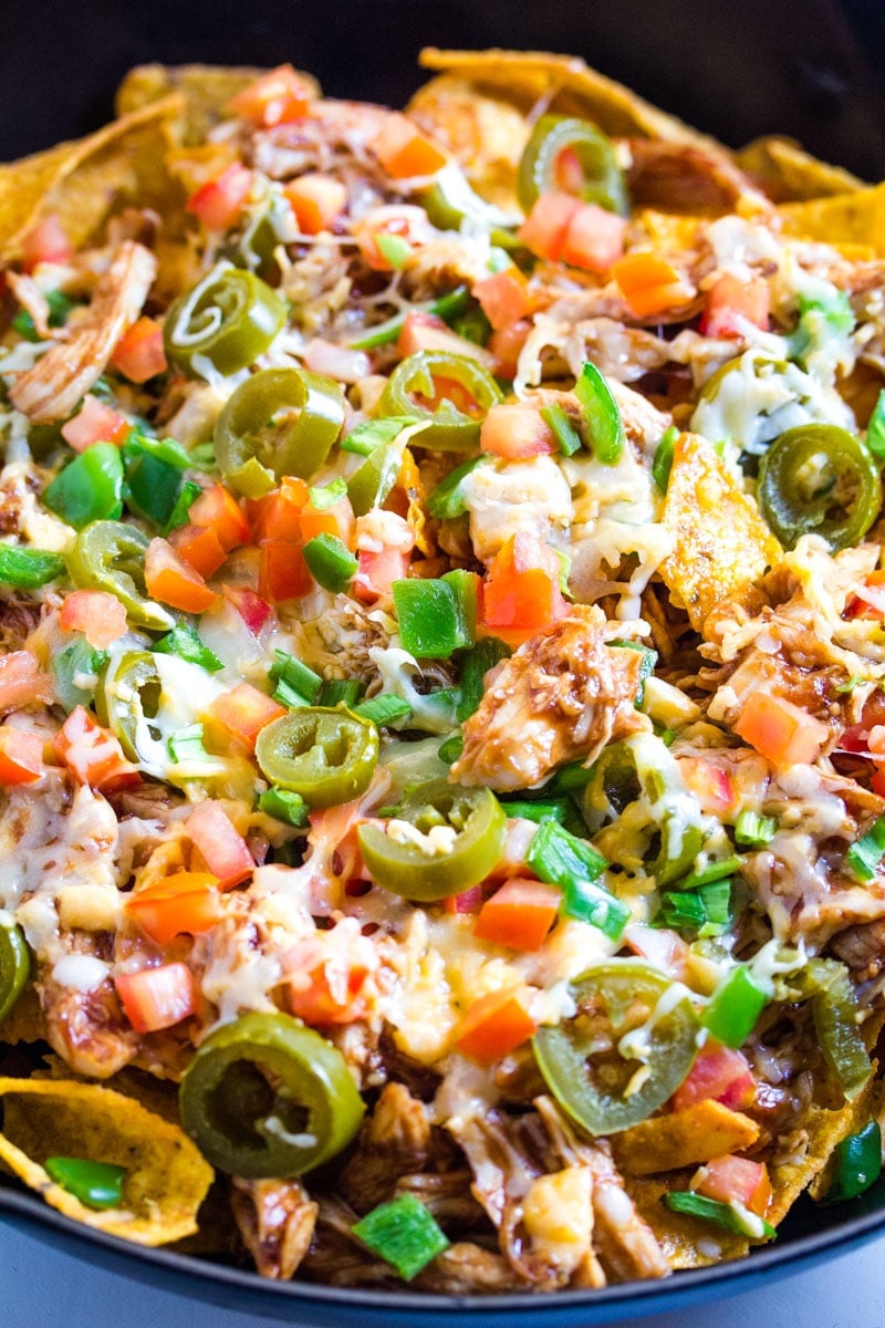 A close up of baked Dorito chips topped with cheese, tomatoes, jalapenos, and bell pepper.