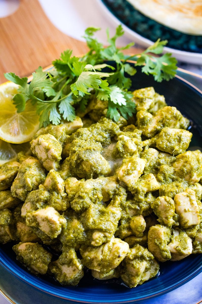 Close up shot of hara masala chicken garnished with fresh coriander leaves and lemon slices.