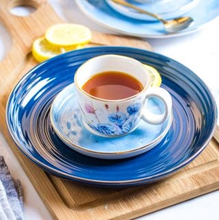 Honey Lemon Tea served in small white patterned cups placed on blue plates.