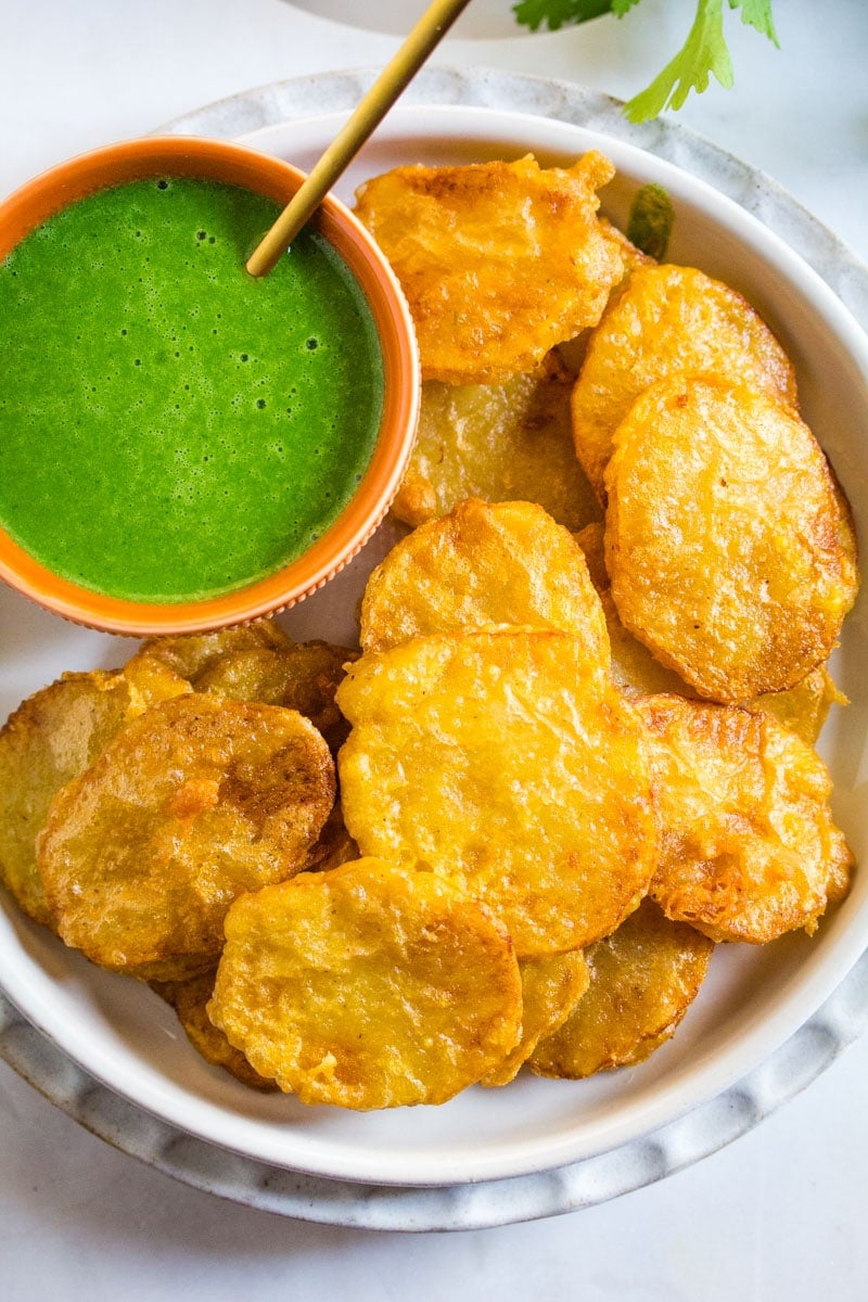 An overhead shot of Indian potato fritters on a light grey plate. 