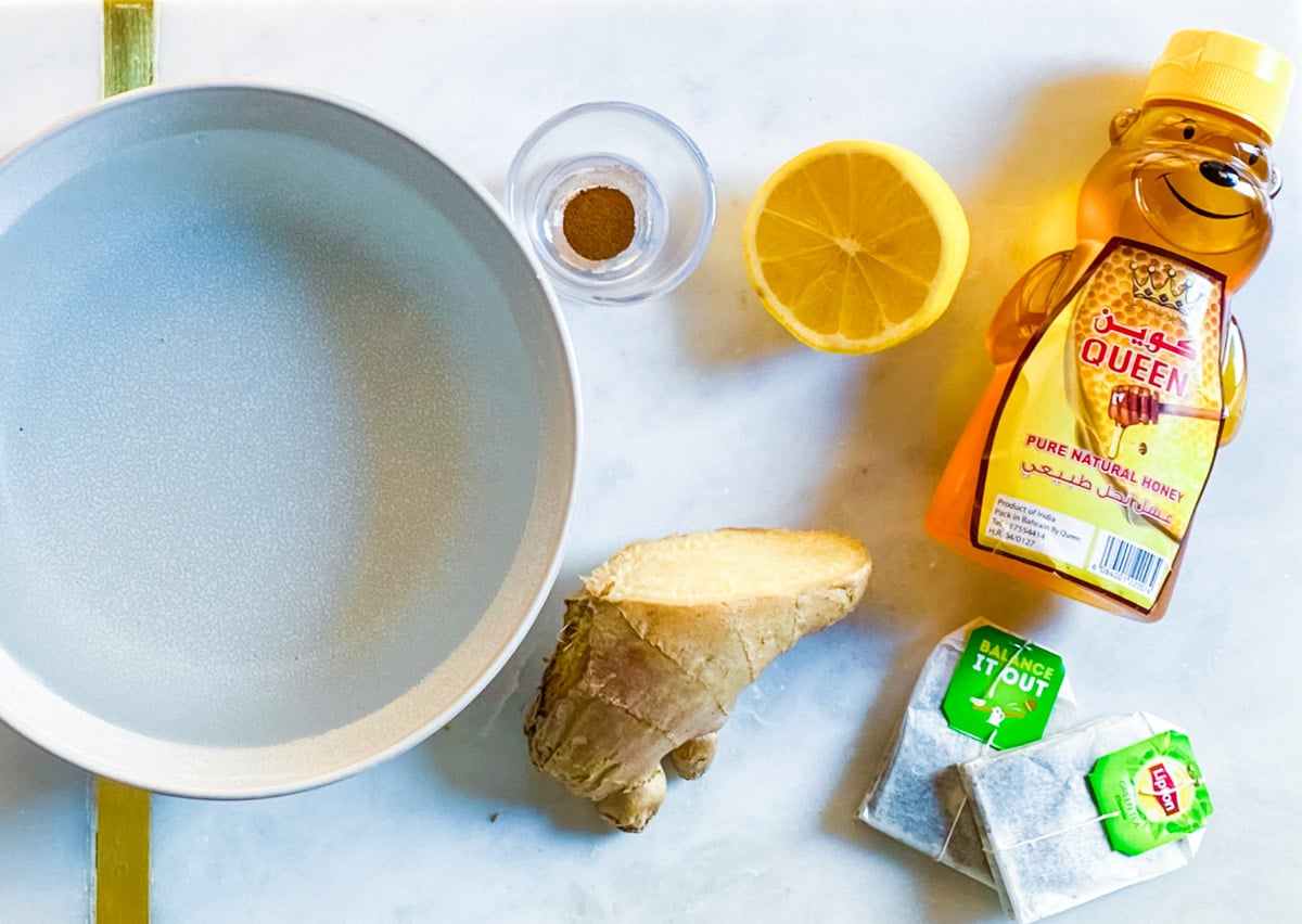 Ingredients needed for green tea placed on a white marble slab.