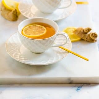 Two cups of green tea with ginger placed on a white background.