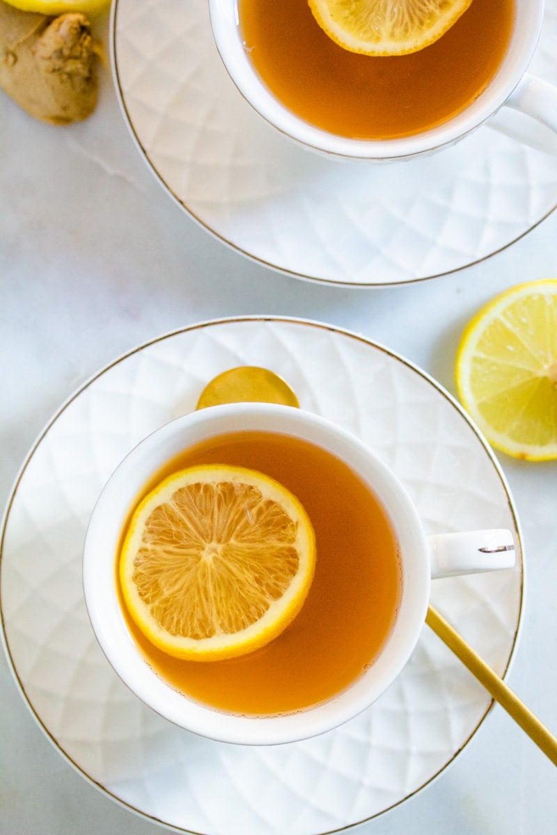 Overhead shot of ginger green tea served in white tea cups.