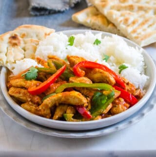 Pakistani Style Chicken Jalfrezi served with naan and rice on a grey plate.