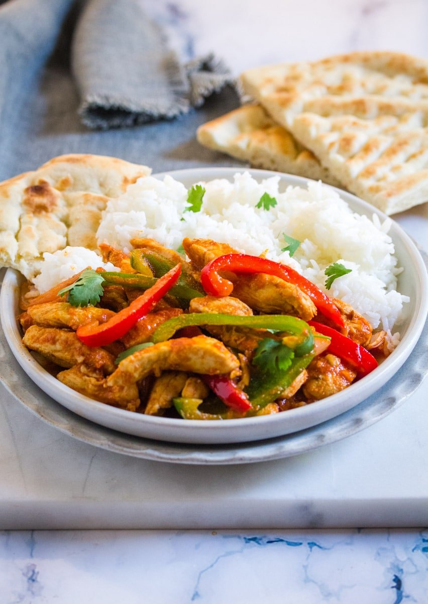 Pakistani Style Chicken Jalfrezi served with naan and rice on a grey plate.