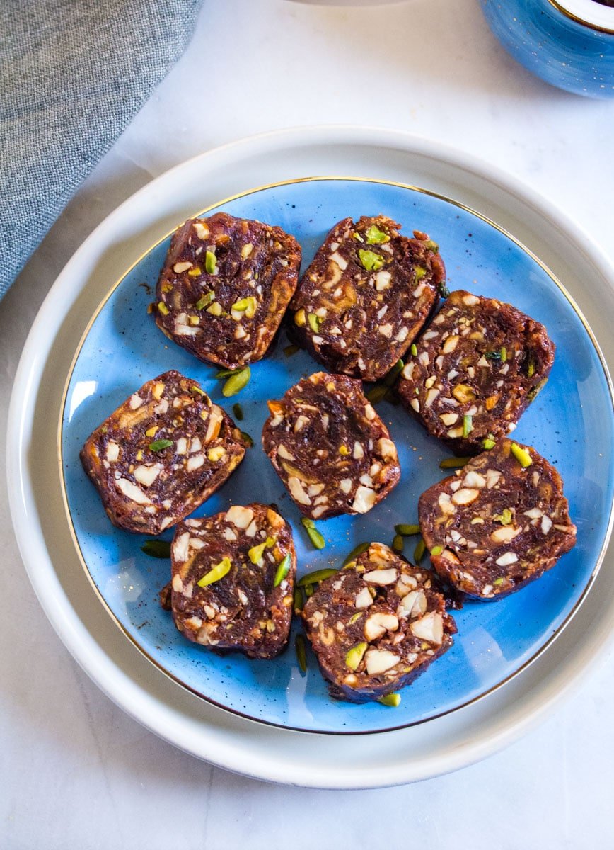 Overhead shot of date and nut roll slices on a bright blue plate.