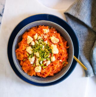 Overhead shot of gajar halwa topped with khoya and slivered pistachios.