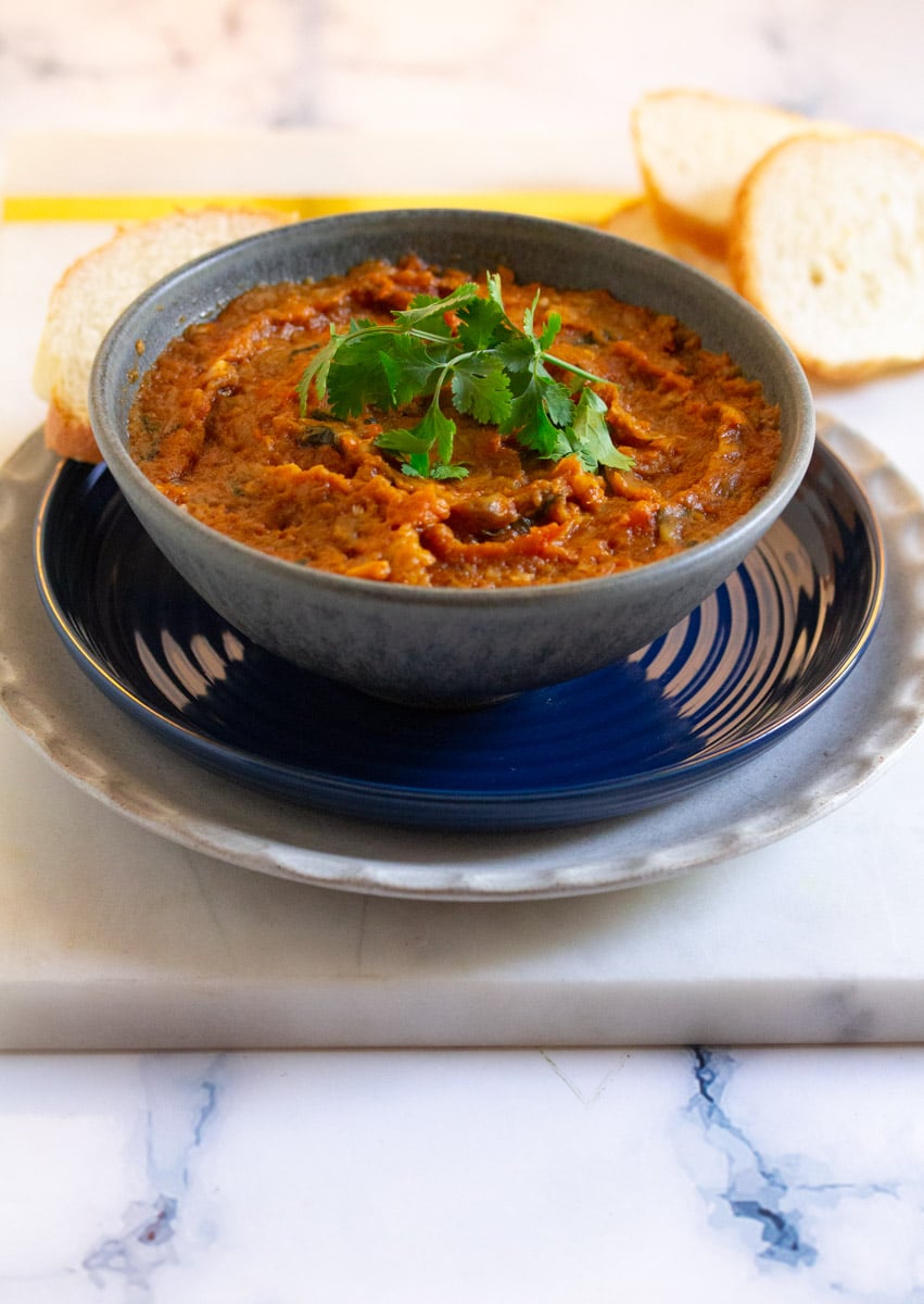 A bowl of zaalouk served with a few slices of french bread.