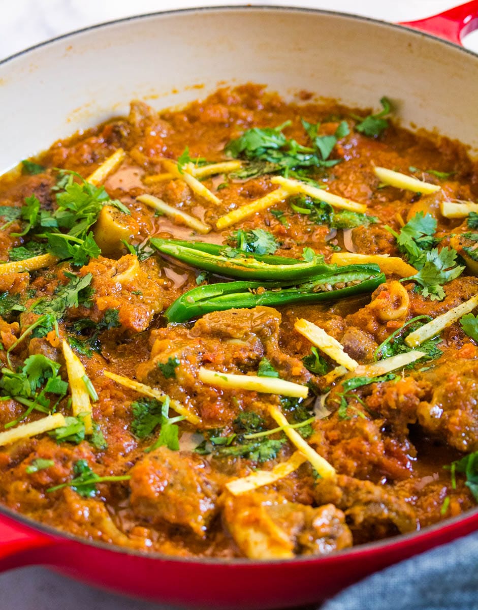 Close up shot of mutton or lamb karahi in a red dutch oven skillet.