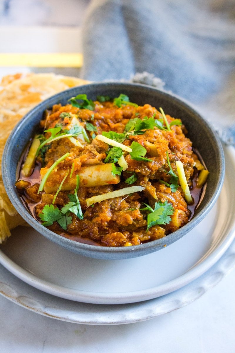Mutton Karahi served in a grey bowl and topped with fresh ginger and coriander.