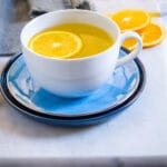 Tea made with orange peel and saffron served in a white mug.