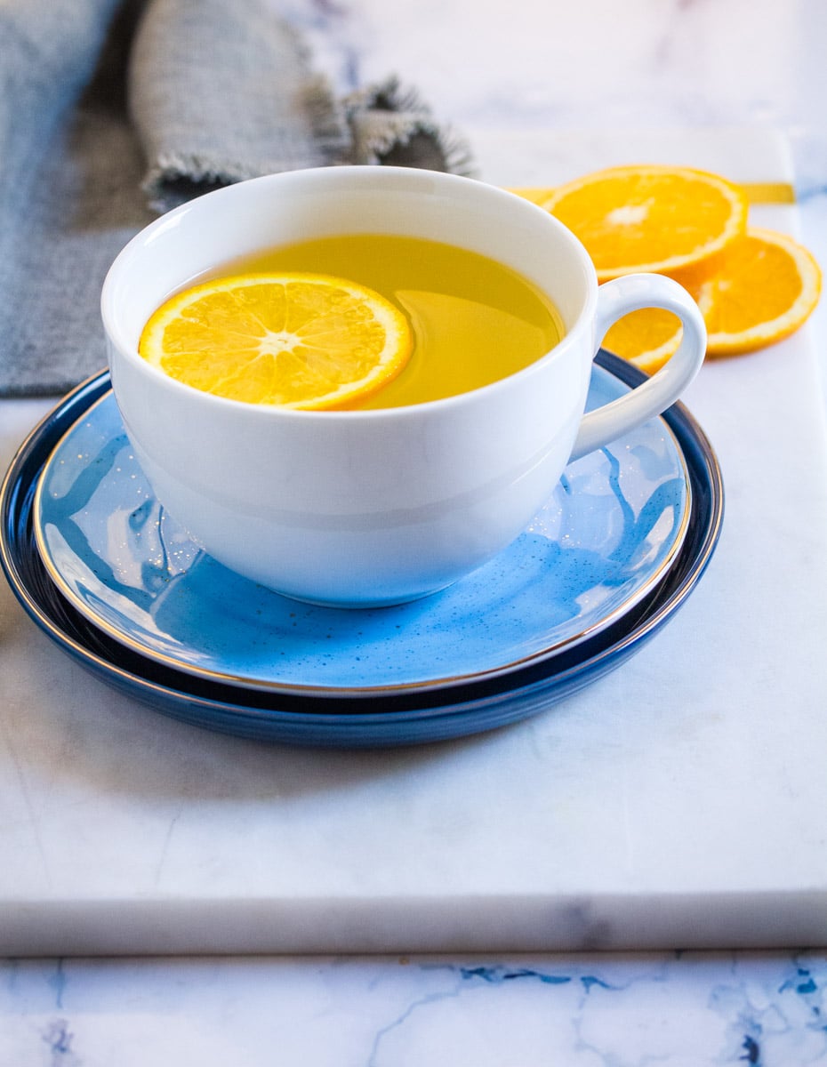 Tea made with orange peel and saffron served in a white mug.