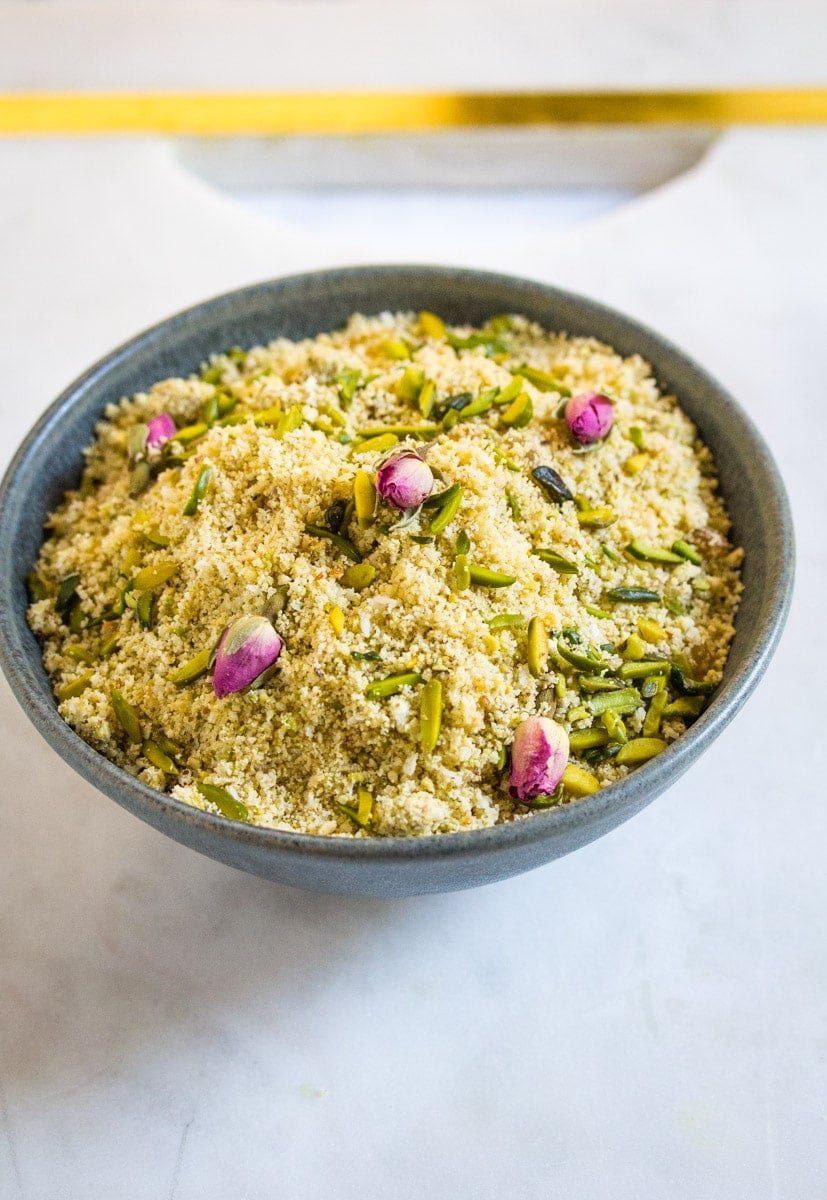 A grey bowl filled with panjeeri placed on top of a marble slab.