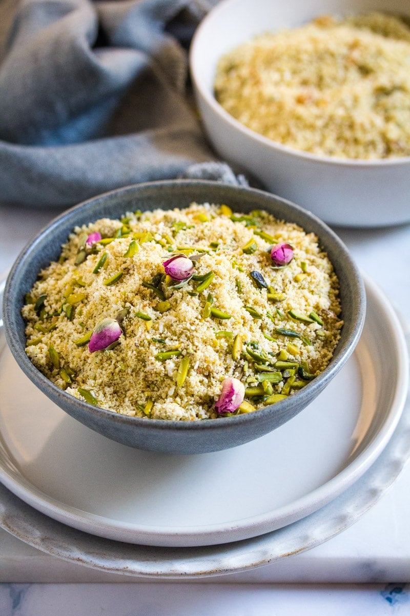 Panjeeri served in a dark grey bowl topped with edible dried rose buds.