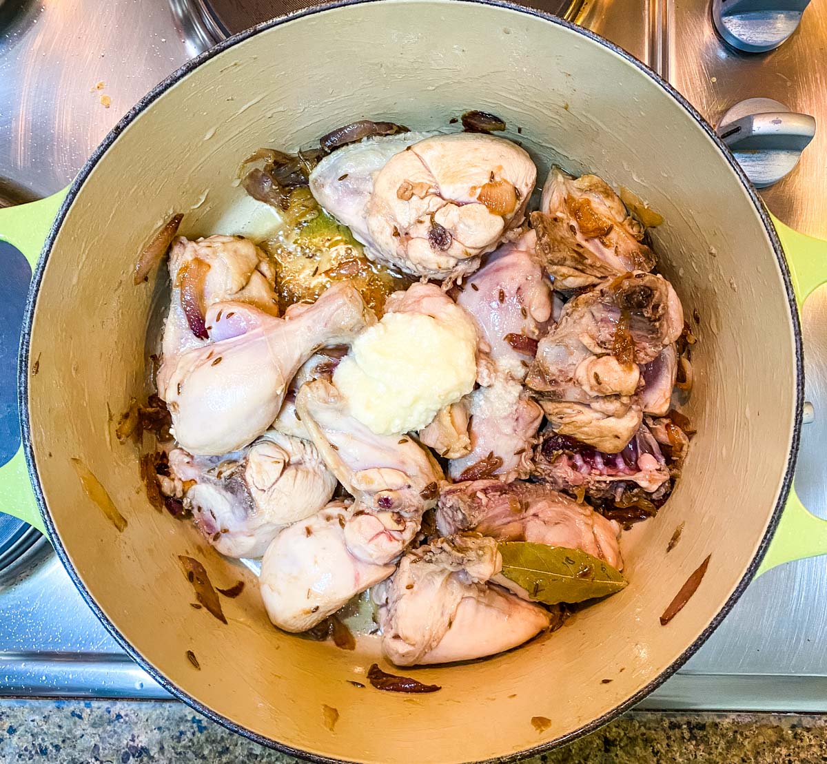 Sauted chicken mixed with ginger garlic paste and whole spices in a pot.