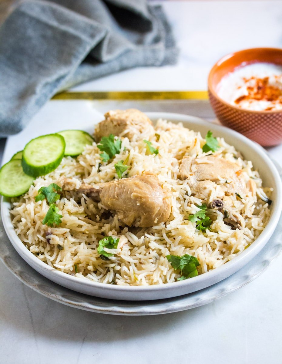 Chicken pulao in a grey plate placed on top of a white marble slap.