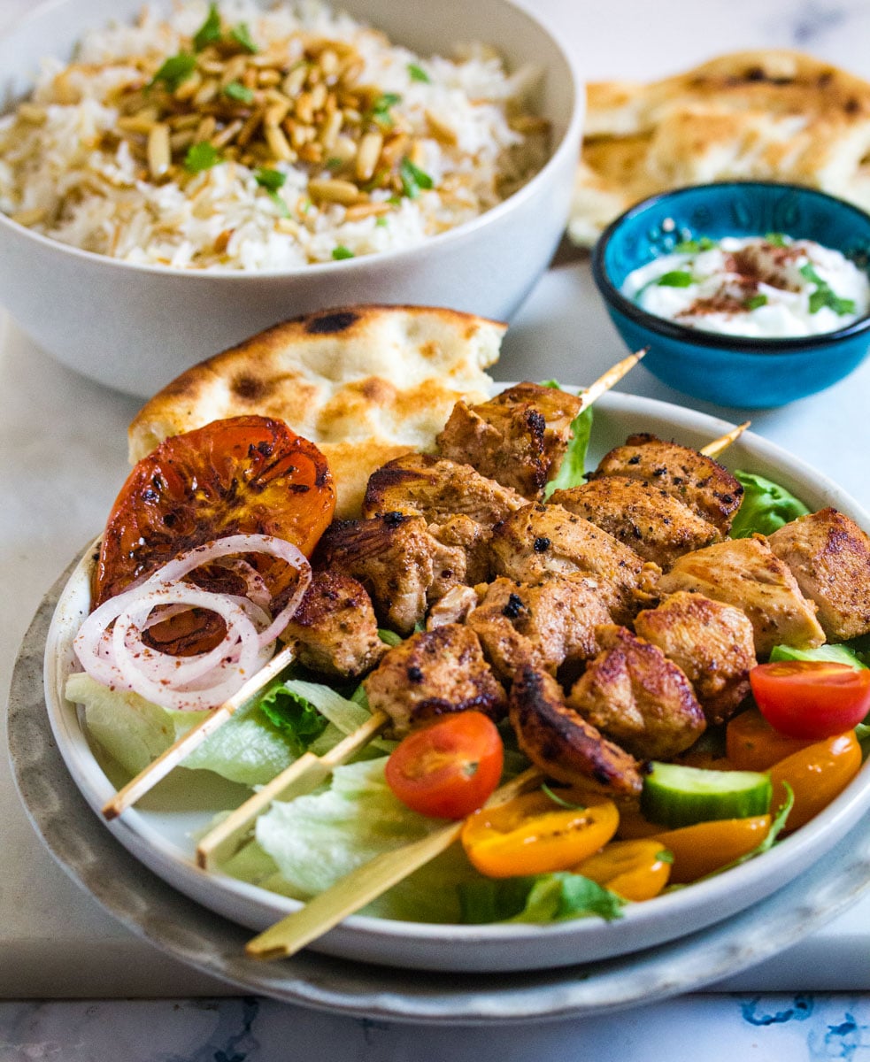 A Lebanese inspired meal with chicken skewers, rice and yogurt. 