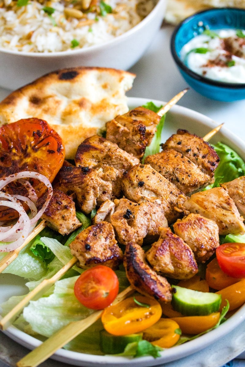 Lebanese chicken skewers served with salad, lebanese rice and a small bowl of yogurt.