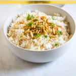 Vermicelli Rice topped with toasted pine nuts and chopped coriander in a white bowl.